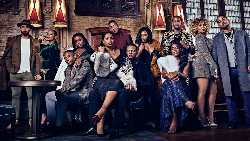 the cast of love and hip hop poses around a couch in a promotional still