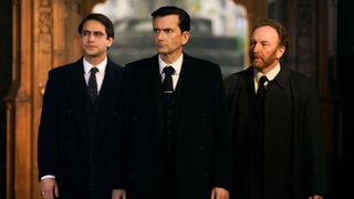 Three men in black suits walk up a church aisle
