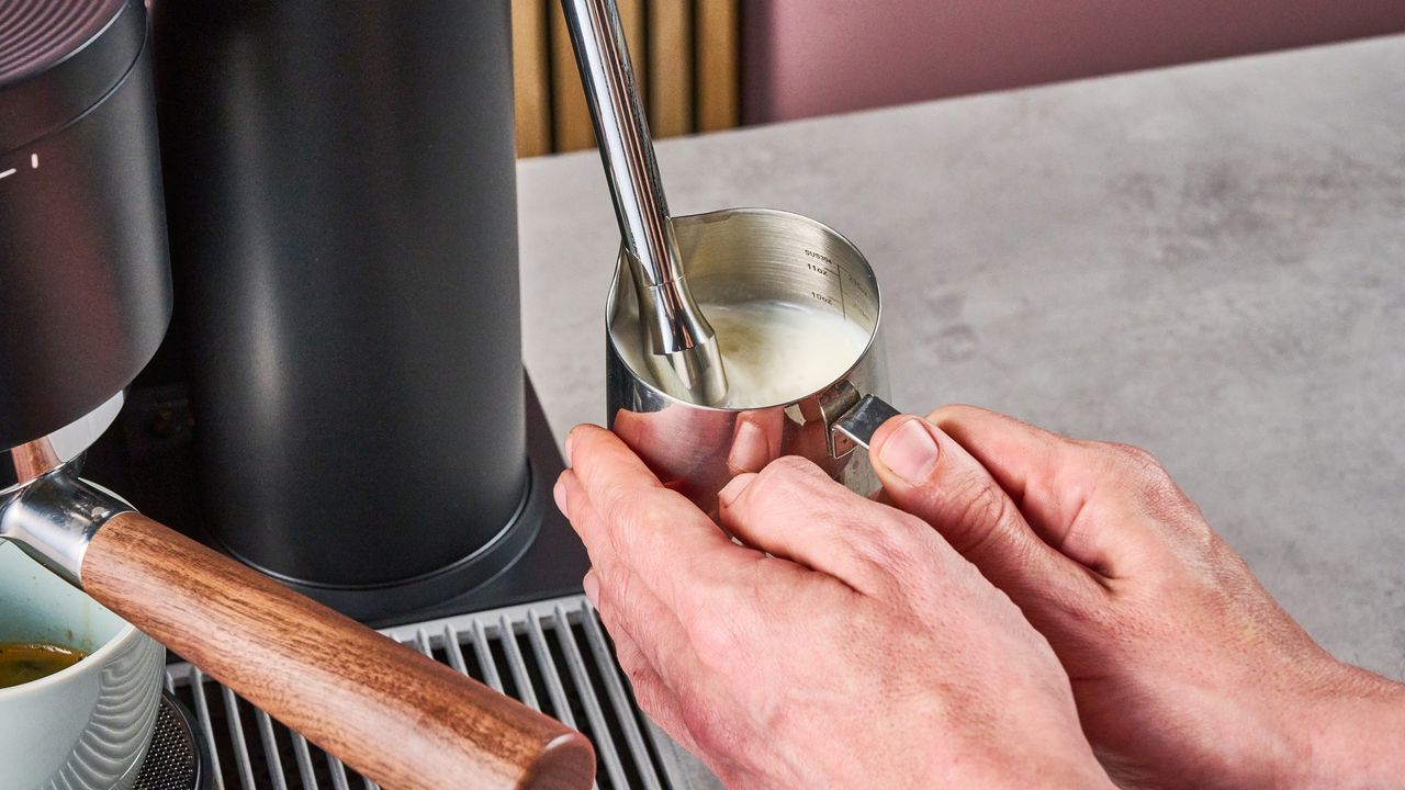 A man steams milk using the Meraki Espresso Machine's steam wand.