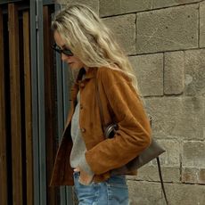  @anoukyve wearing a brown suede jacket, sweater, and jeans.