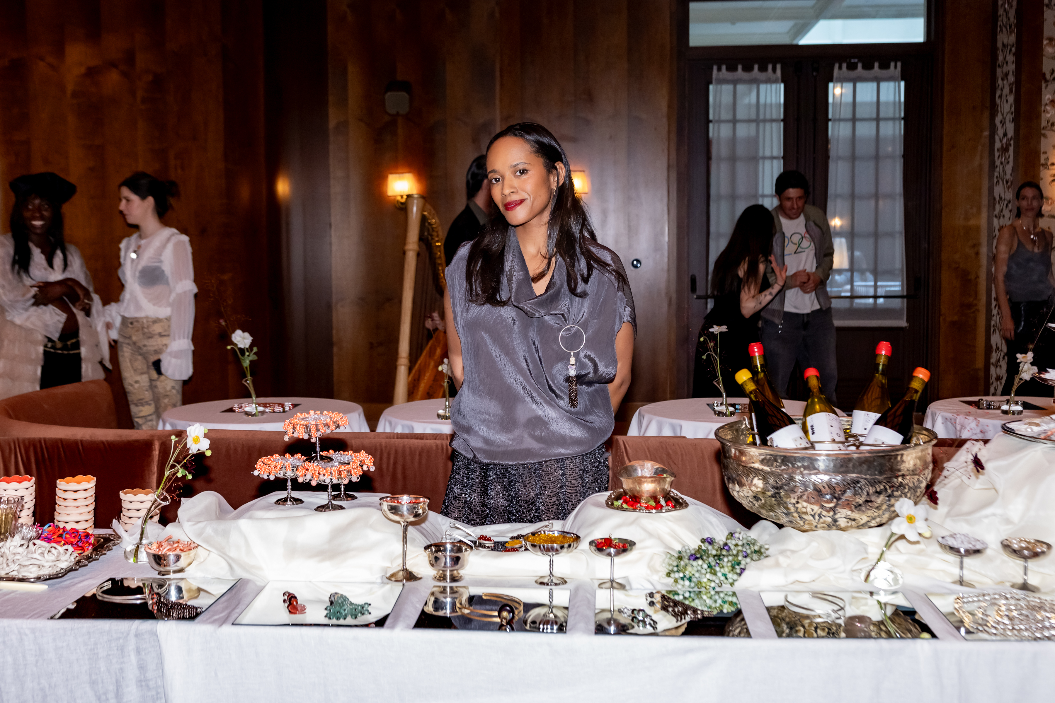 Don't Let Disco jewelry designer Ashley Moubayed at her Spring 2025 NYFW event wearing a gray top and skirt with a beaded tassel charm