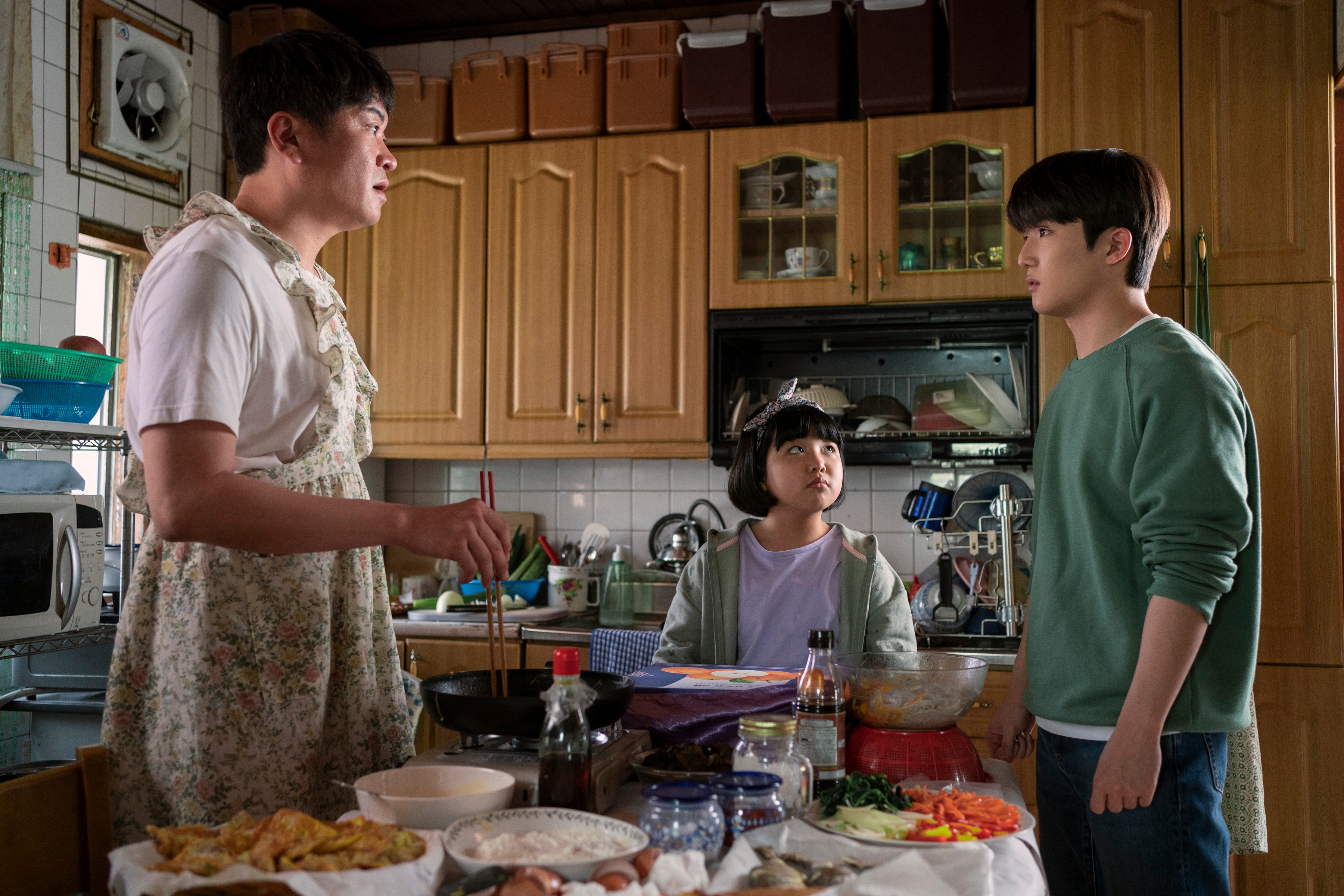 Lee Hyung-chul talking to his children in a busy kitchen in xo kitty