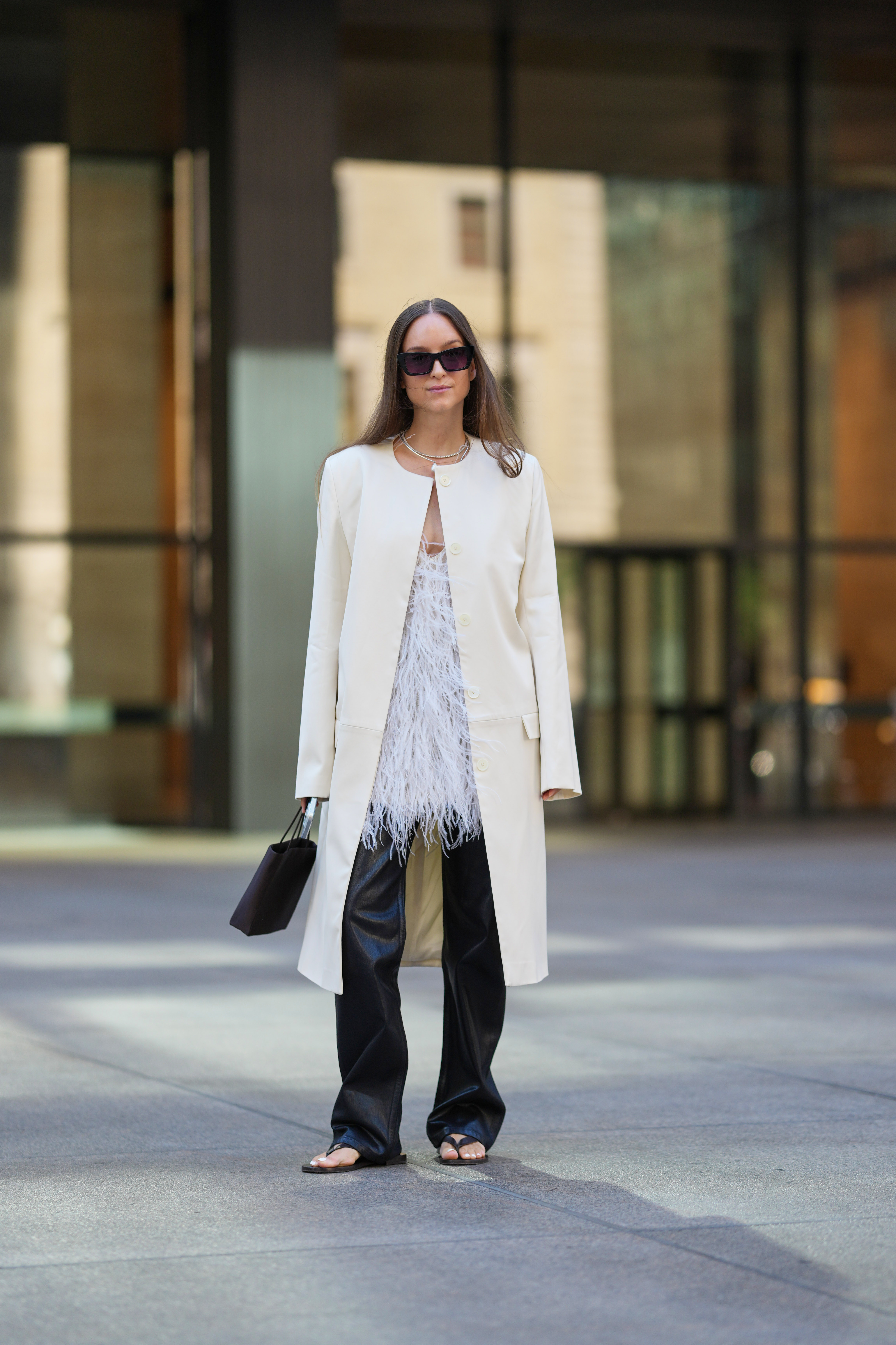 a woman wearing black leather trousers and a white coat