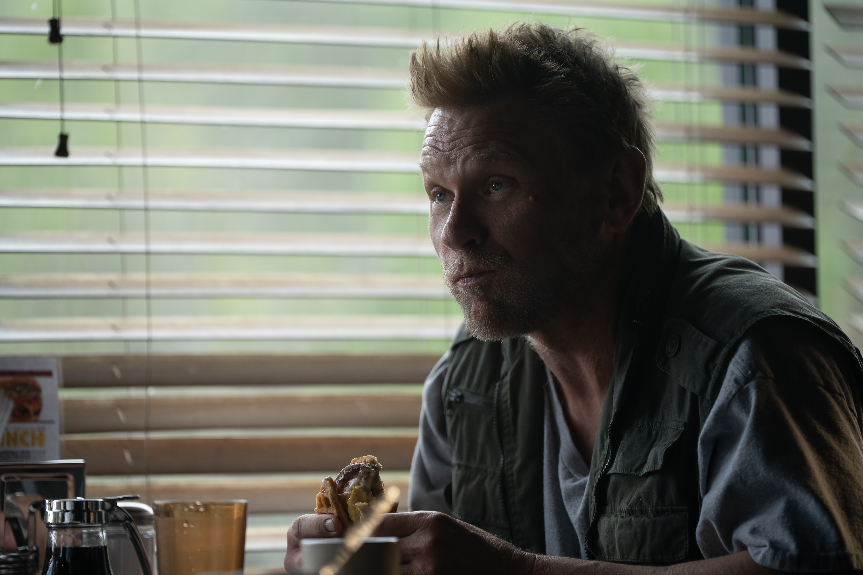 Mark Pellegrino as curtis edward smith wearing a green vest sitting at a diner table in murdaugh a death in the family