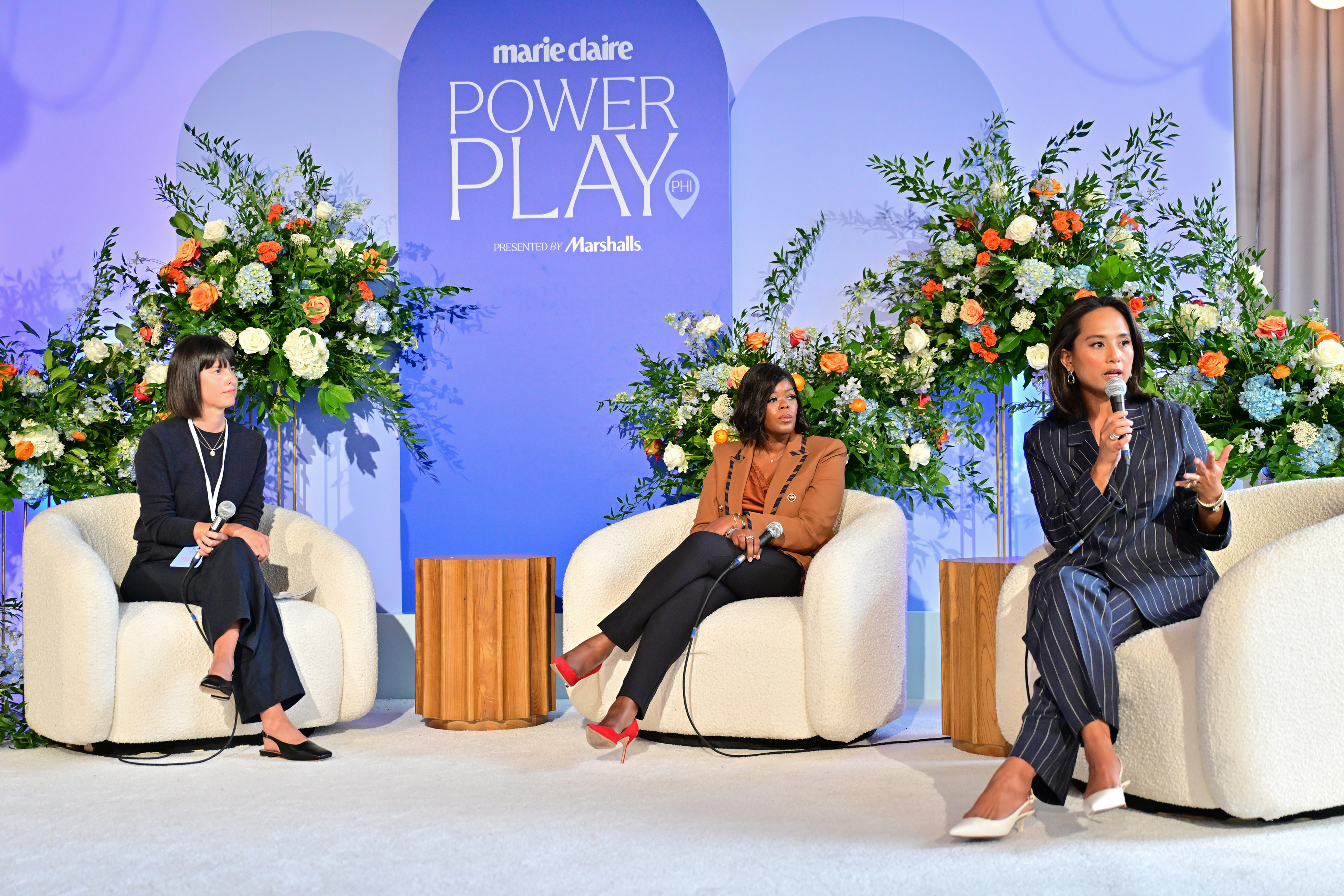 Marie Claire executive editor Andrea Stanley moderates a panel with Bugaboo CMO Jeanelle Teves and entrepreneur Tina Wells during the &amp;ldquo;Leadership in 2025&amp;rdquo; session at Power Play Philadelphia, seated on stage against a backdrop of flowers and the event logo.