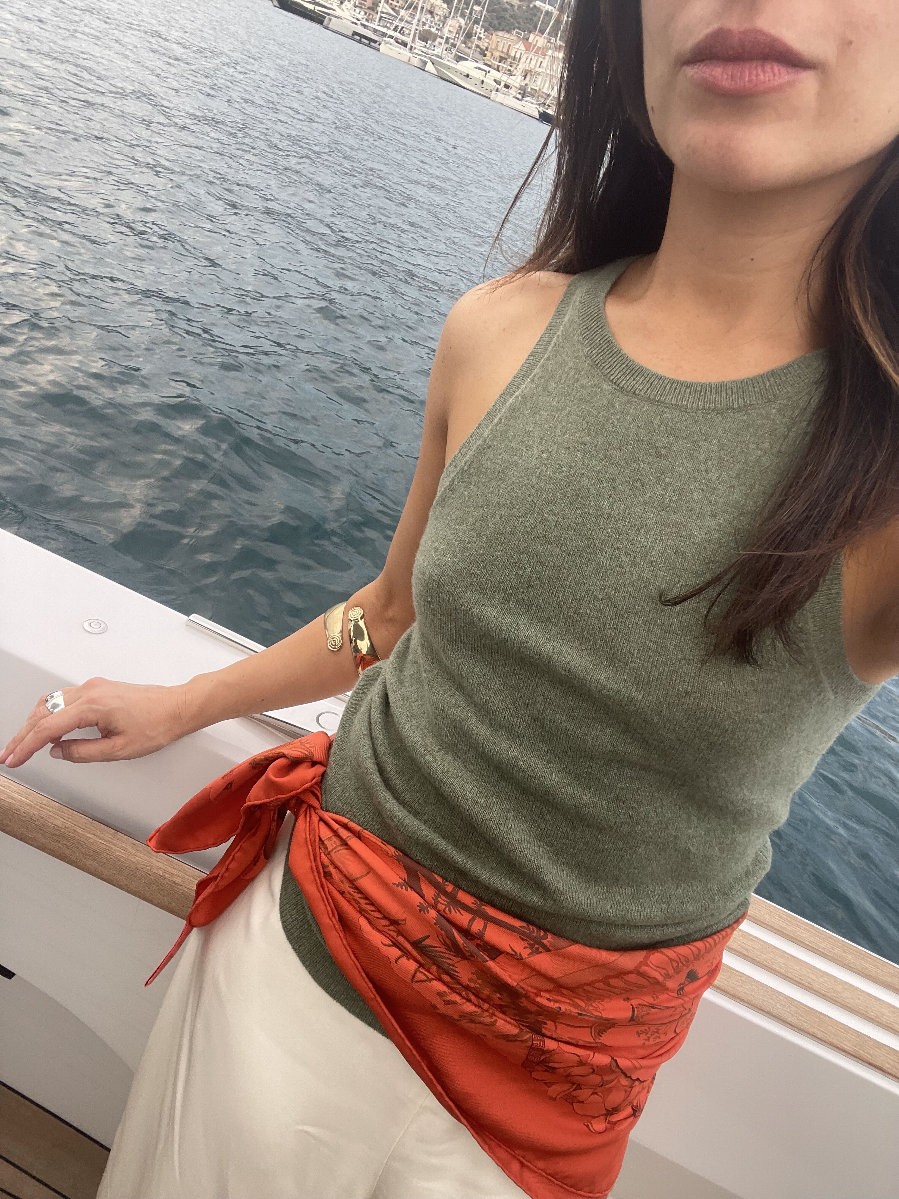 Juju Ferentinos in a green tank, white satin pants, and a red scarf as a belt