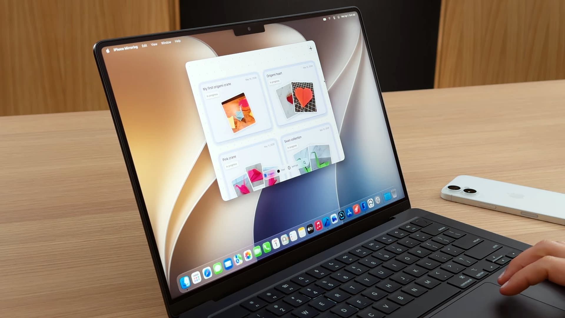 A person using iPhone Mirroring on a MacBook Pro running macOS 27 Golden Gate.