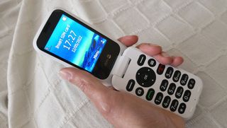 Bedste mobiler til seniorer: En person, der holder en hvid Doro 6880 med &aring;ben sk&aelig;rm.