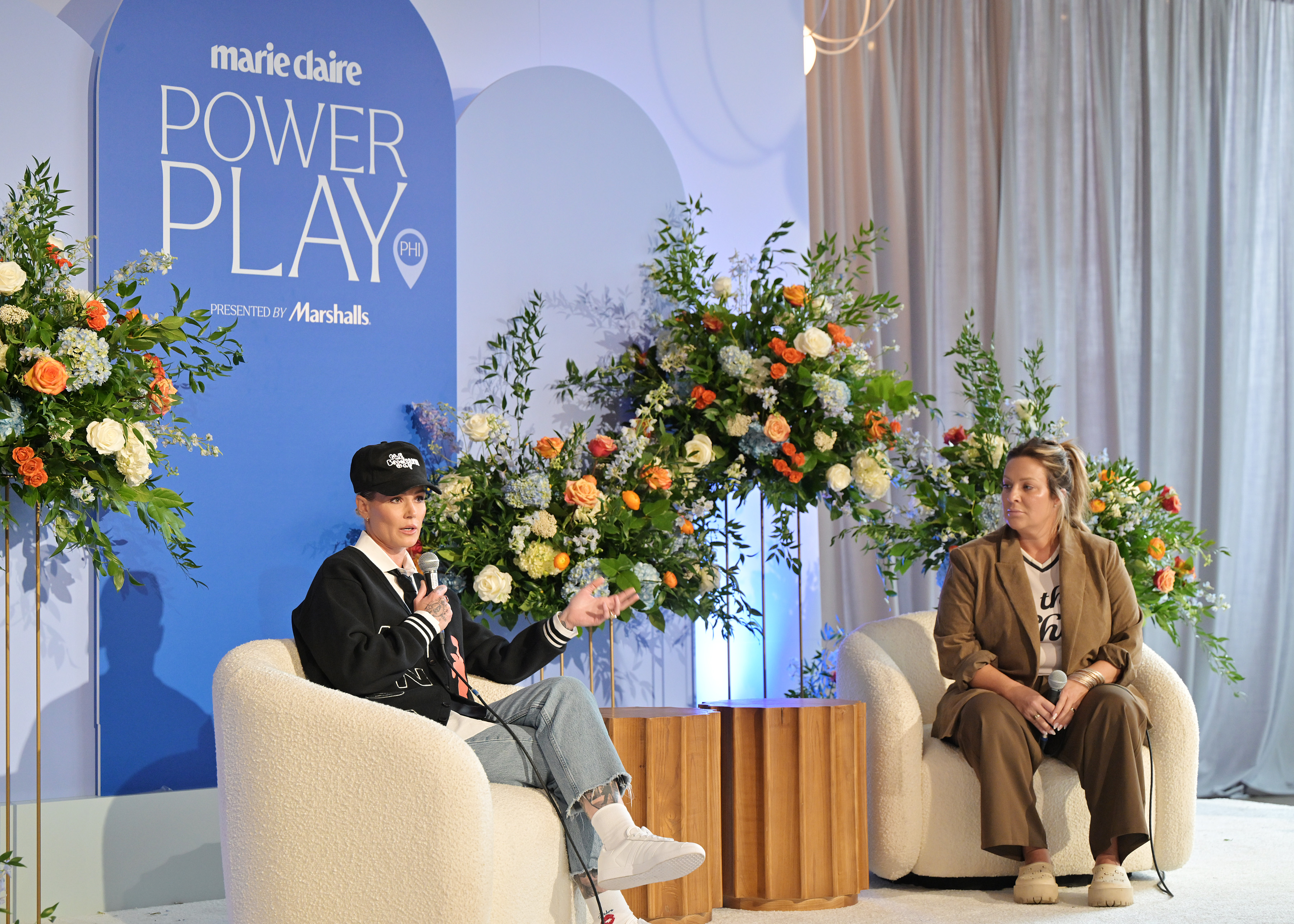 Former soccer star Ashlyn Harris and Deep Blue Sports + Entertainment founder Laura Correnti speak during a fireside chat at Marie Claire&amp;rsquo;s Power Play summit in Philadelphia, seated on stage against a backdrop of flowers and the event&amp;rsquo;s logo.