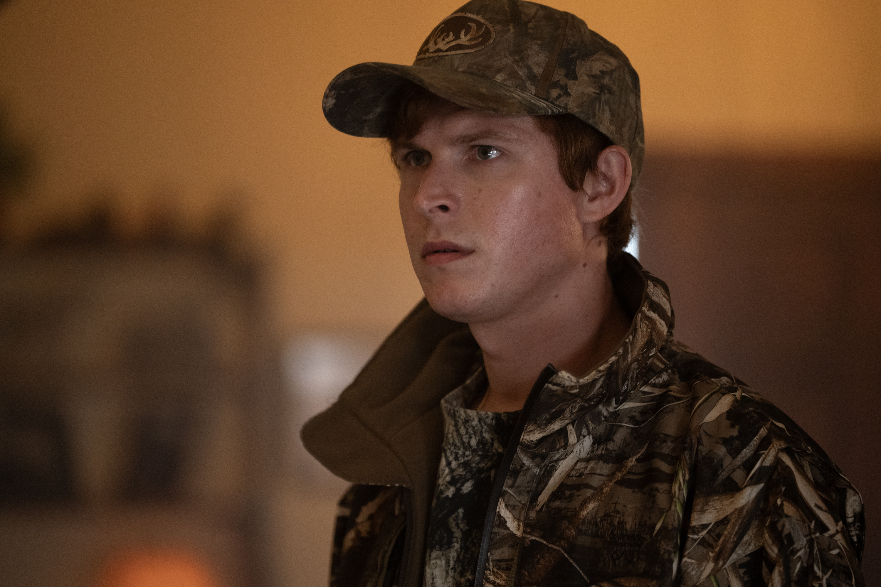 Johnny Berchtold as Paul Murdaugh wearing a camo jacket and baseball cap in murder a death in the family