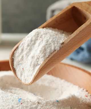 A wooden scoop with laundry powder in it