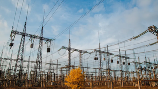 Electrical pylons and high voltage power lines are behind a barbed wire fence. critical infrastructure