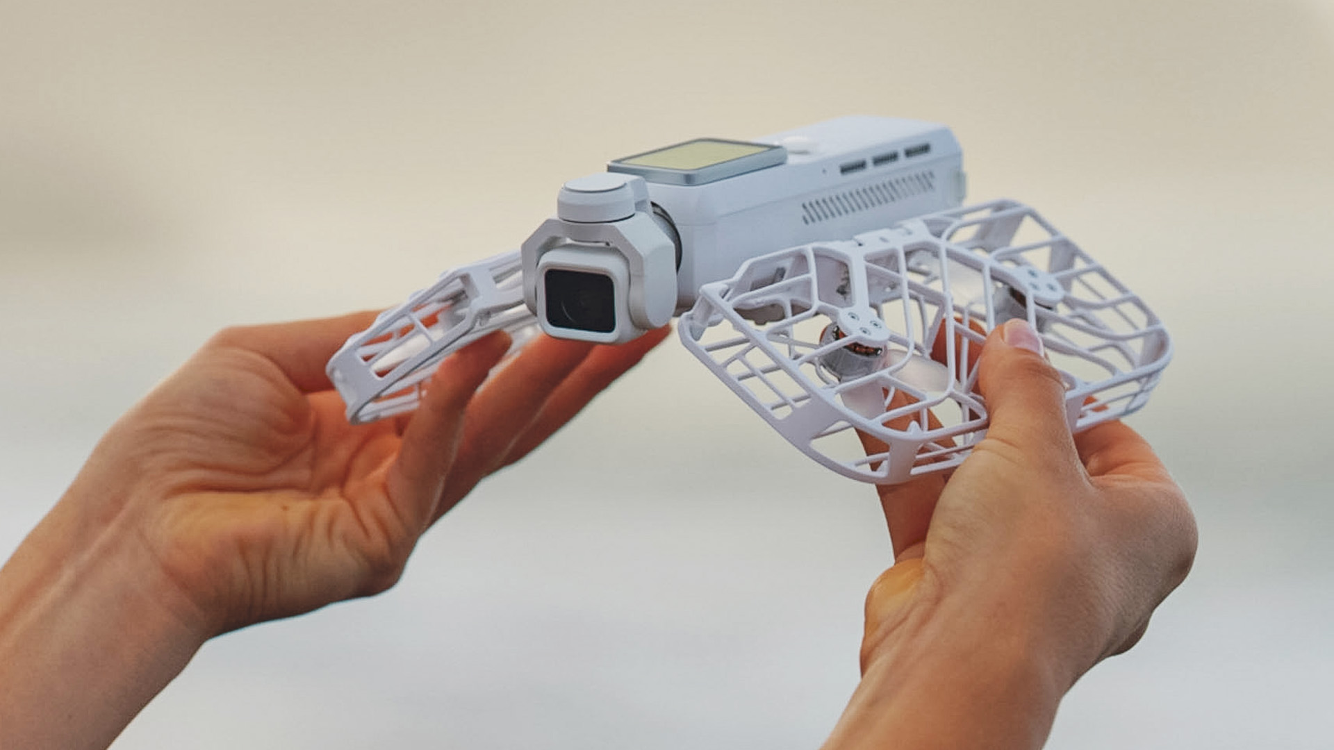 HoverAir Versa drone in user's hands, they are folding the propellor guards away