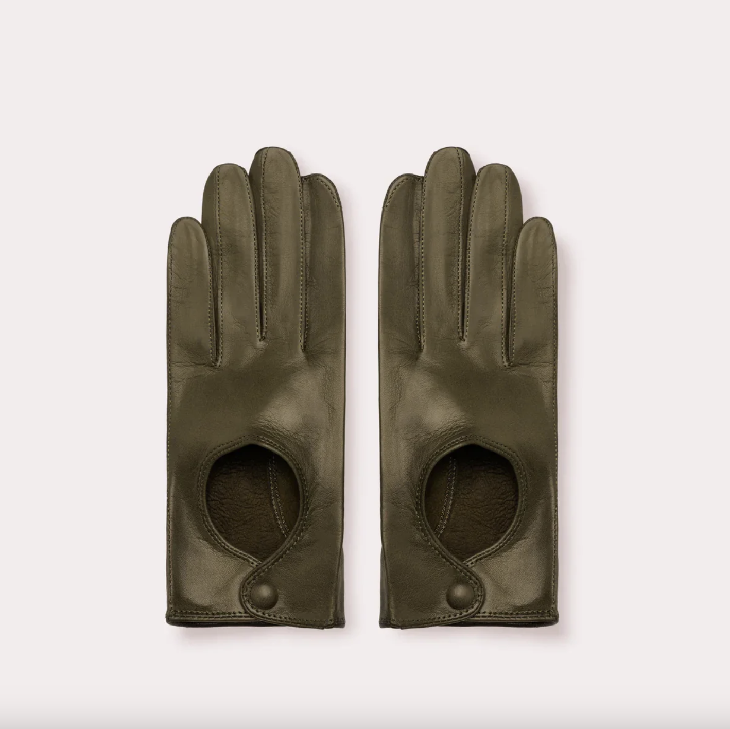 a pair of olive seymoure driving gloves in front of a plain backdrop