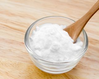 Baking soda in glass bowl with wooden spoon