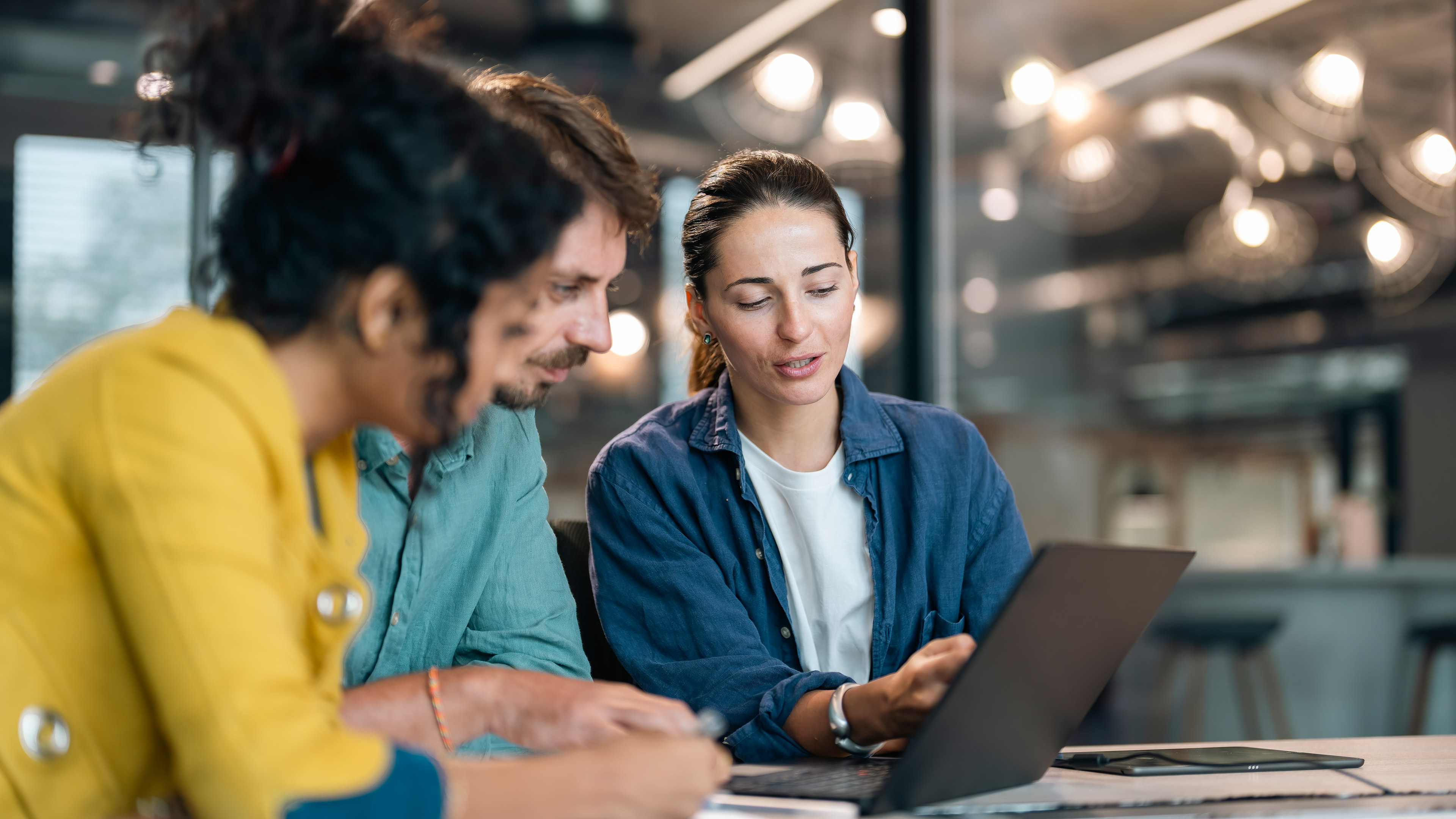 Three office workers sitting together in front of a laptop in an office