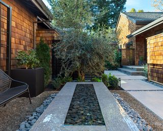 A shaded outdoor area with a water feature and a single chair