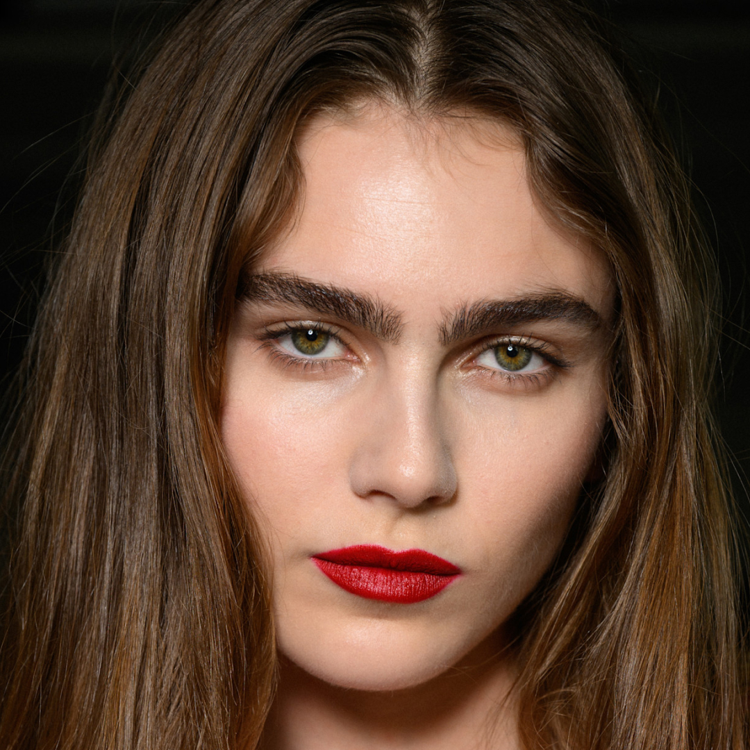 A model wearing red lip liner and lipstick.