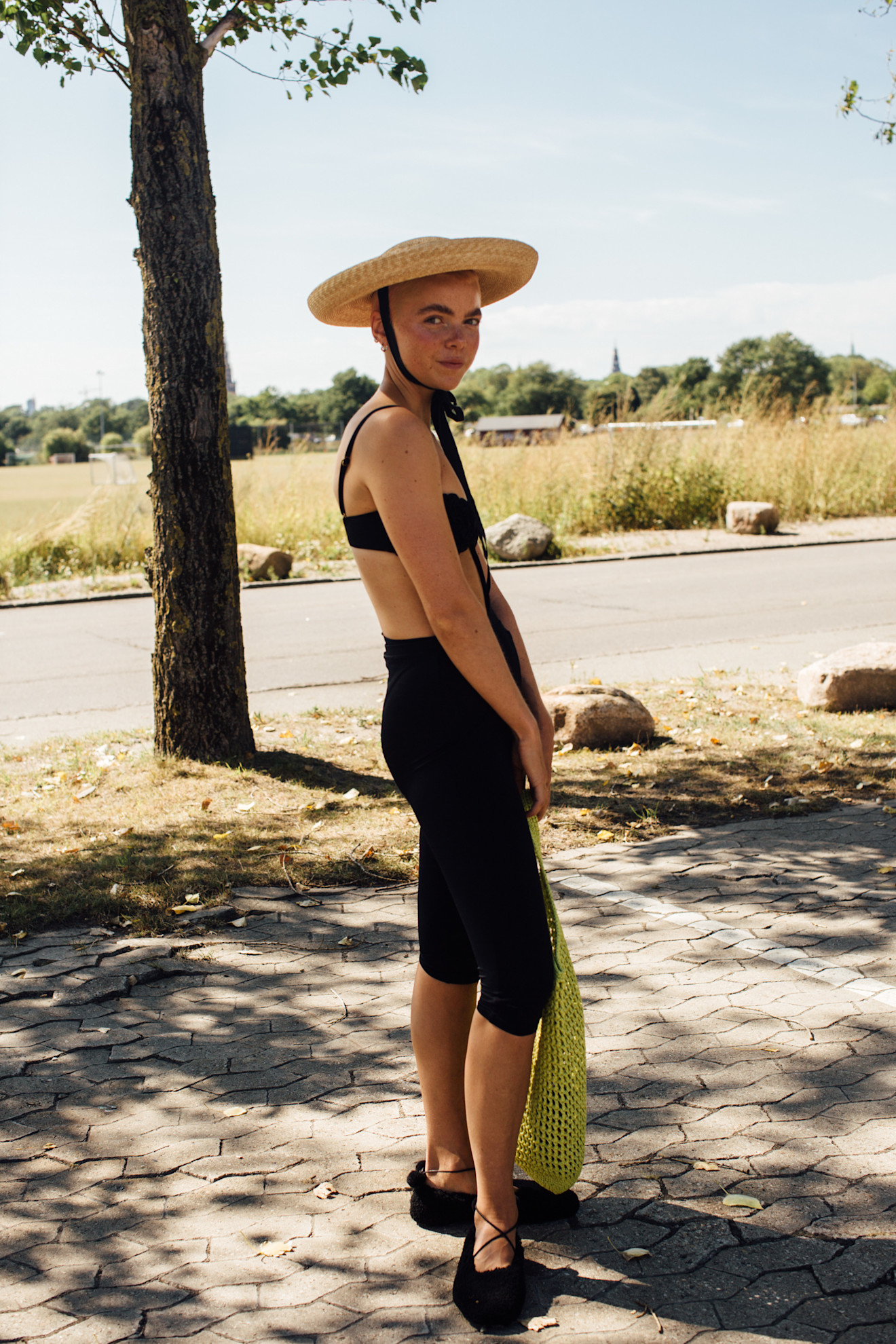 a woman at copenhagen fashion week in a black bikini, capris, and a straw hat