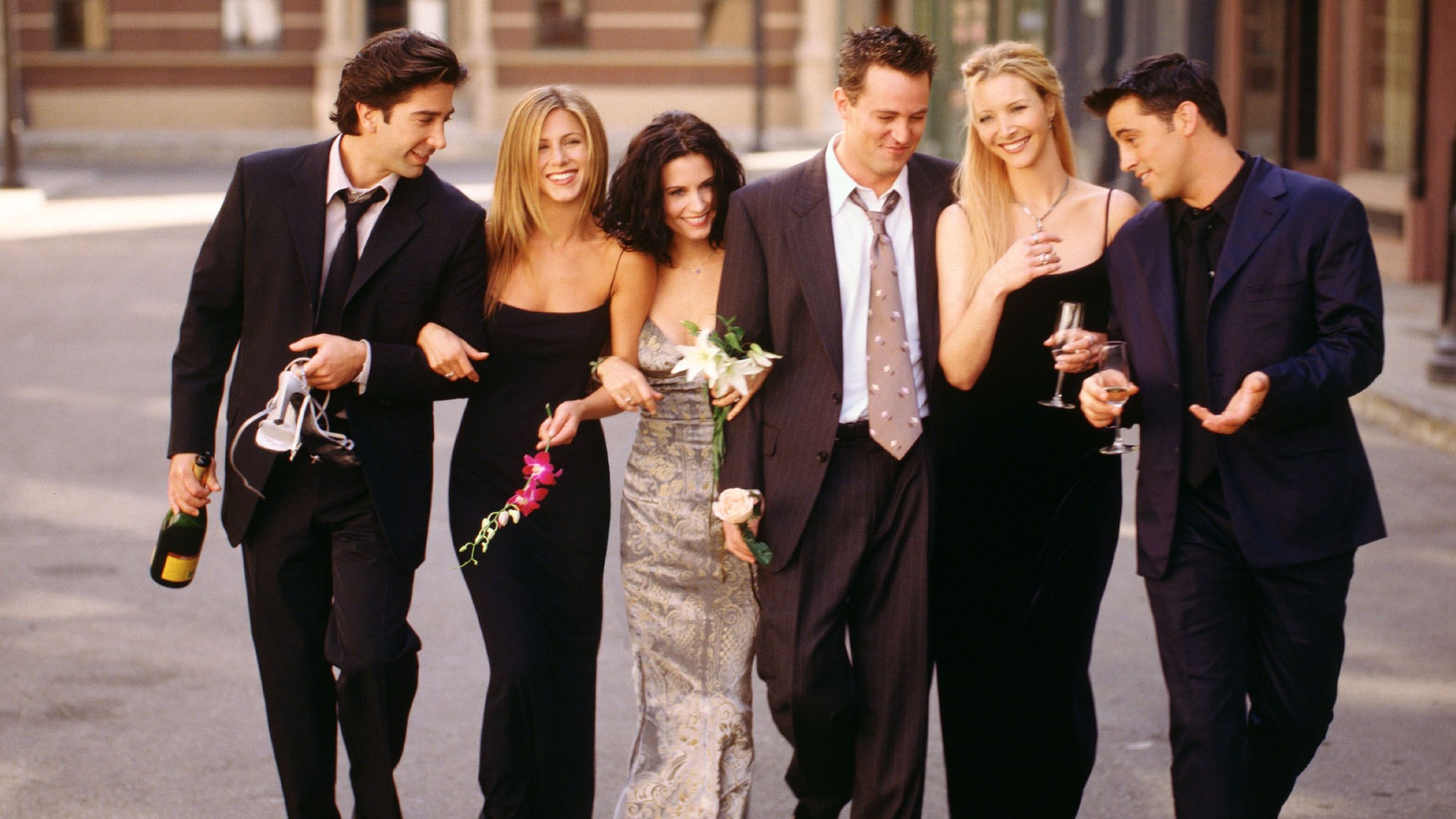 a promotion shot of the friends cast wearing formal wear walking down a new york city street