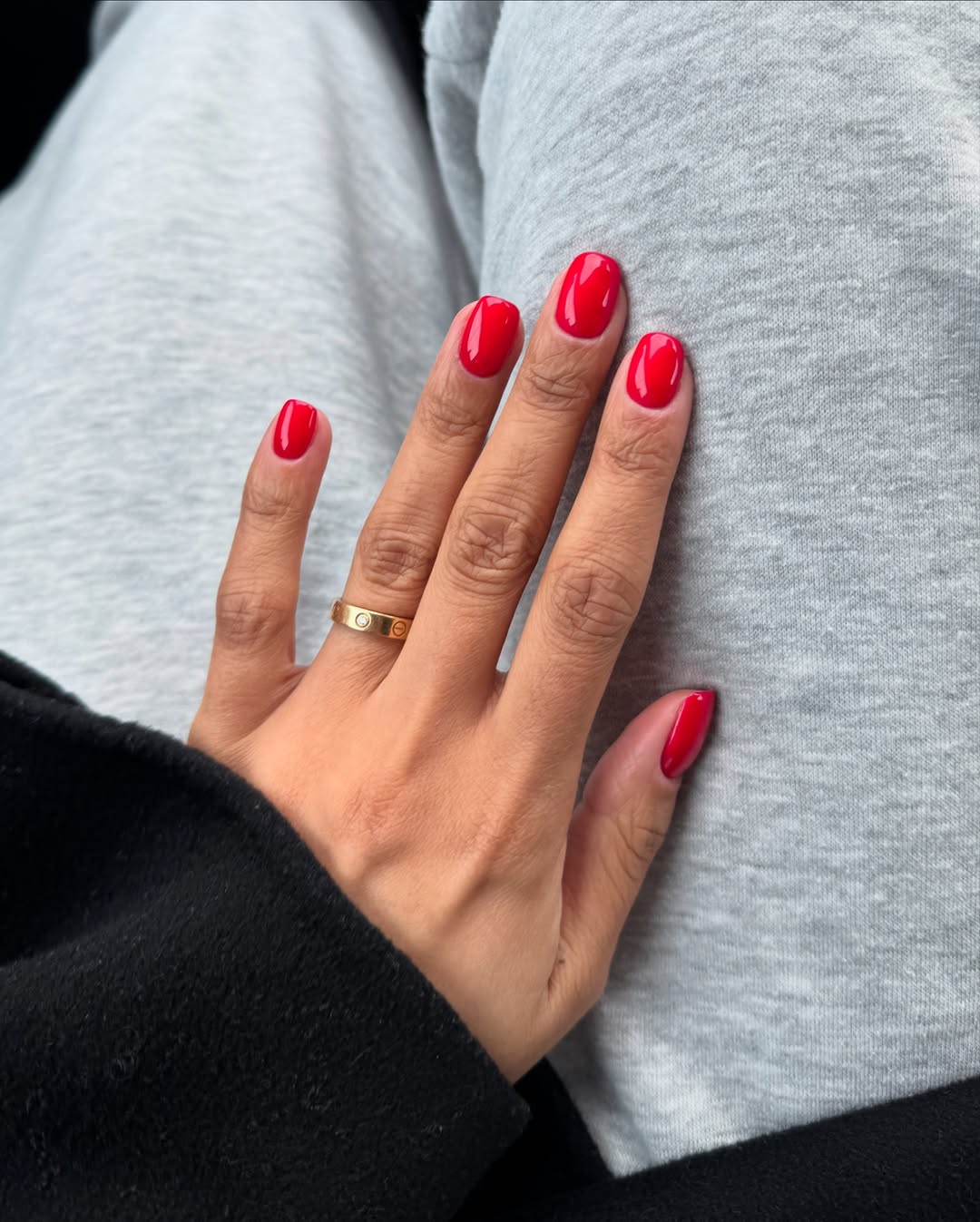 a person with bright red nails and gray sweatpants