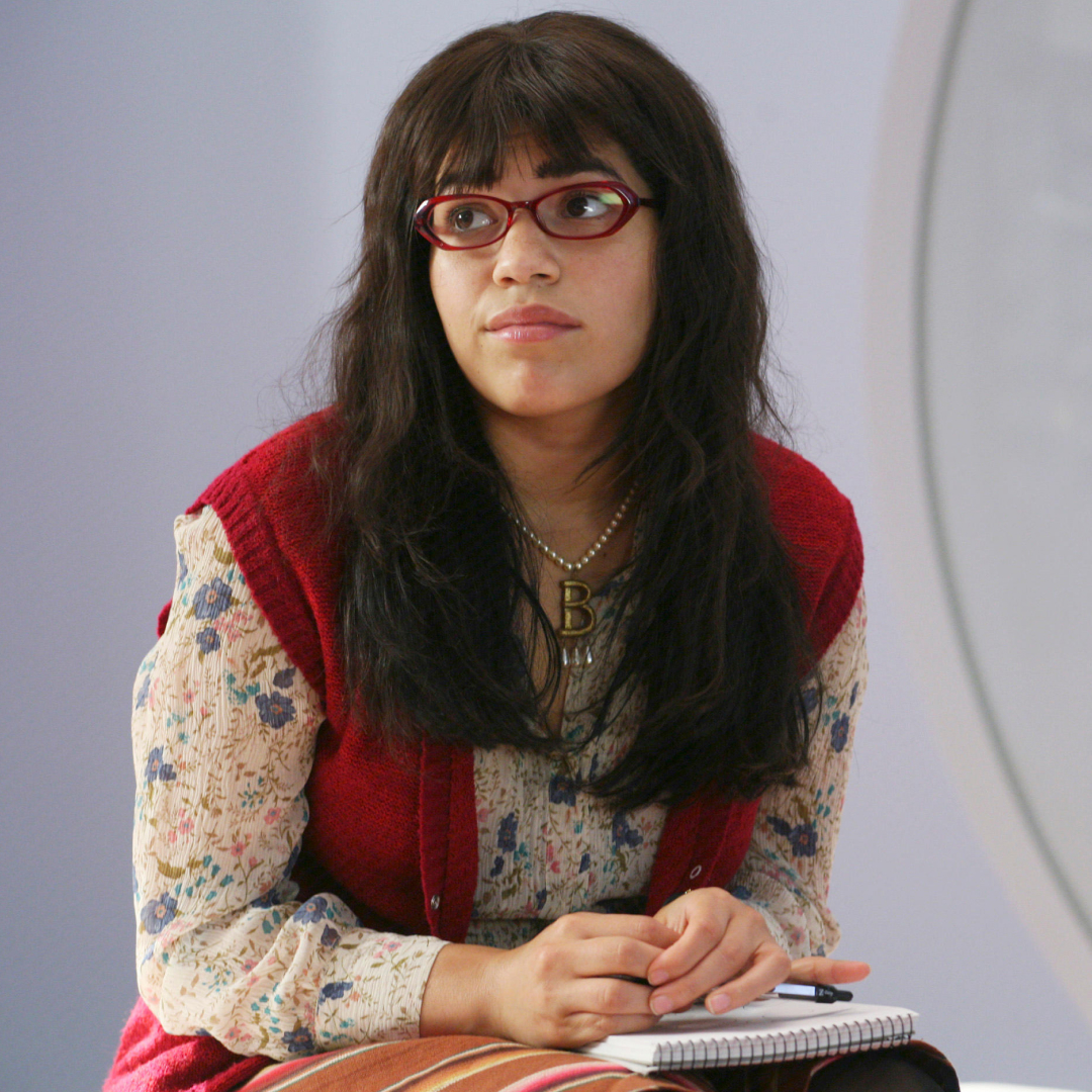 america ferrera in ugly betty sitting with a notebook on her lap