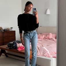 L.A. woman takes a mirror selfie in a The Row sweater, vintage skinny jeans, a black belt and black flats. 