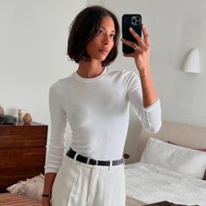 @tylynnnguyen wearing a white 3/4 sleeve white tee with white trousers and a black belt.