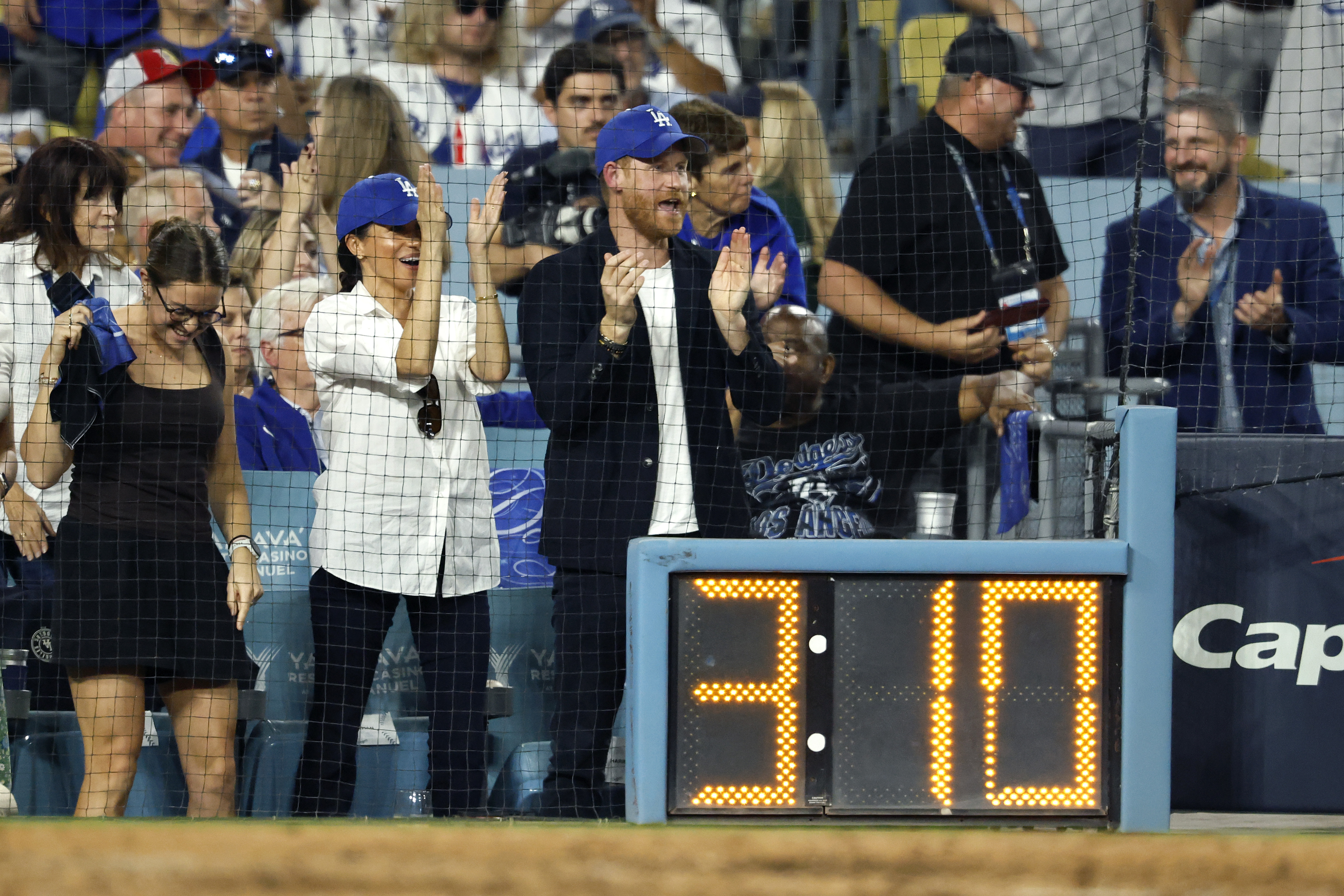 Meghan Markle and Prince Harry standing up clapping at the World Series