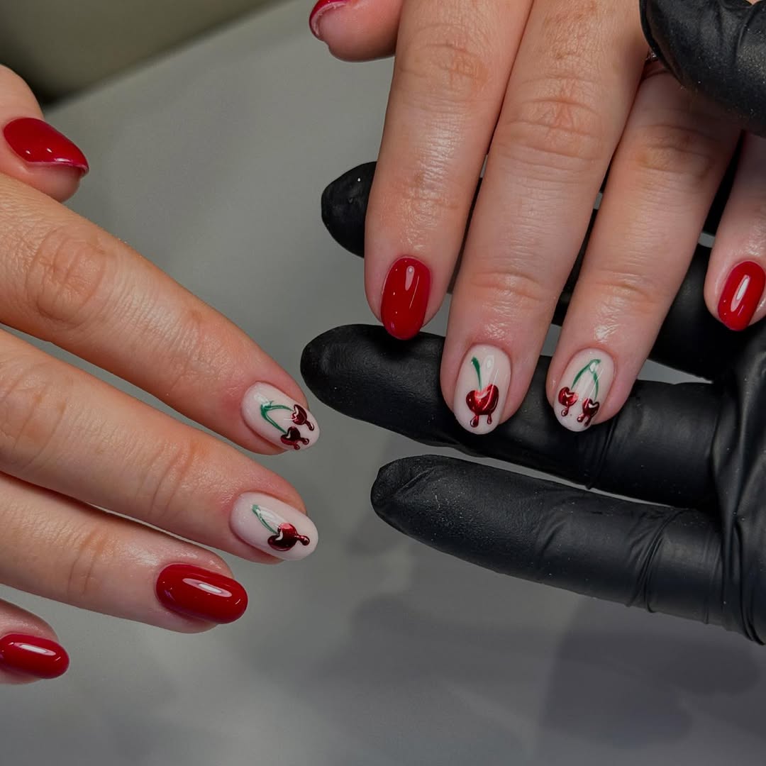 a person with red nails with a cherry chrome design