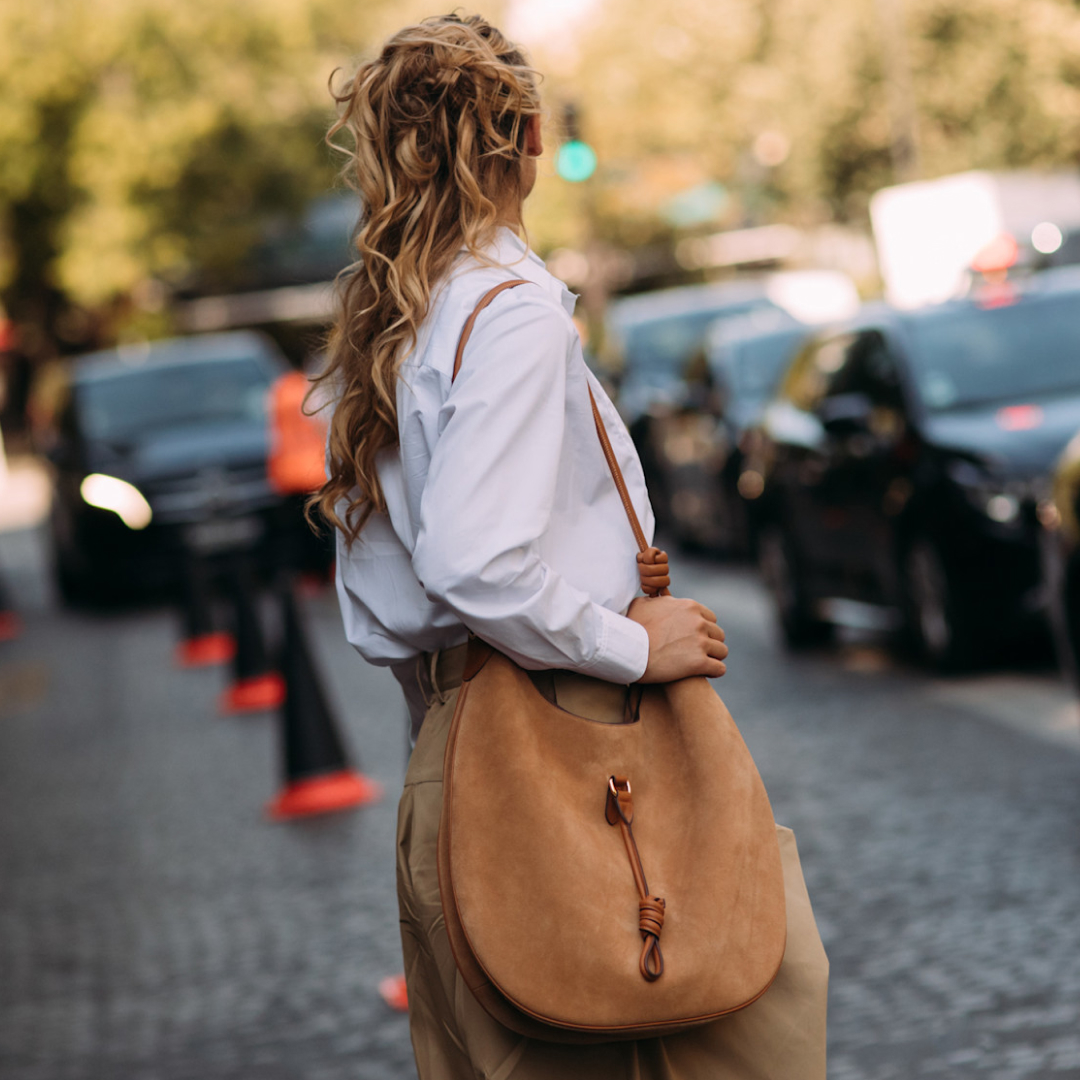 Blonde fashion week attendee looking away carrying a suede bag