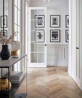 Narrow hallway ideas with slimline console table, herringbone flooring and monochrome color scheme.