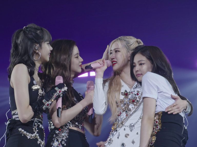 A still from the movie Blackpink: Light Up the Sky of the entire band embracing each other on stage