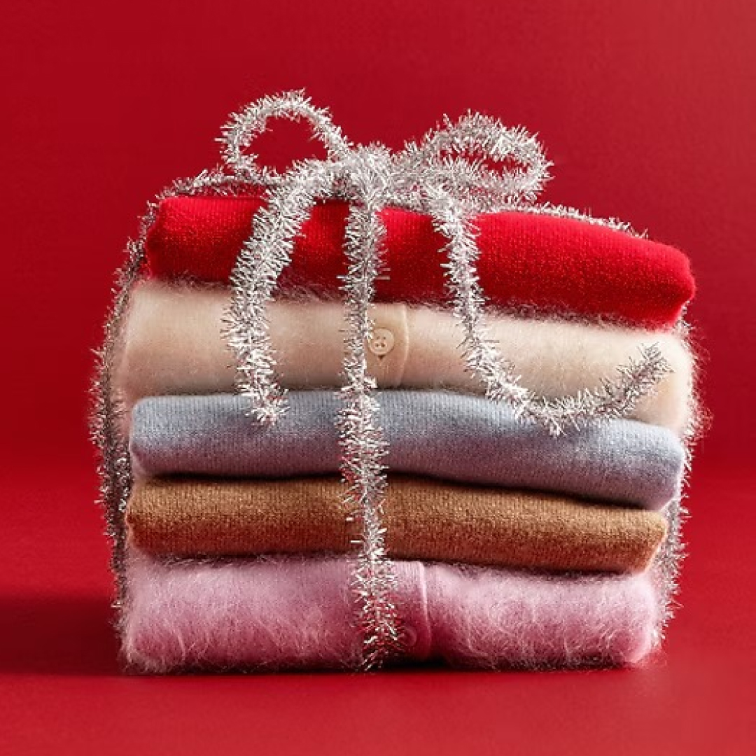J.crew sweaters folded in a stack wrapped in silver tinsel on red background