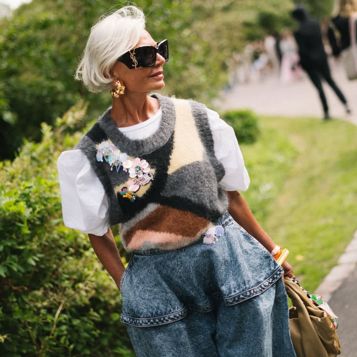 grece ghanem wears sunglasses, a knitted vest and jeans