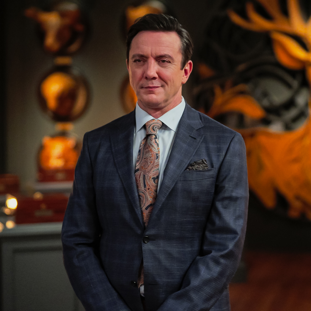 Host Peter Serafinowicz, standing in a room decorated with a wall design of a golden stag, in episode 101 of 'Million Dollar Secret.'
