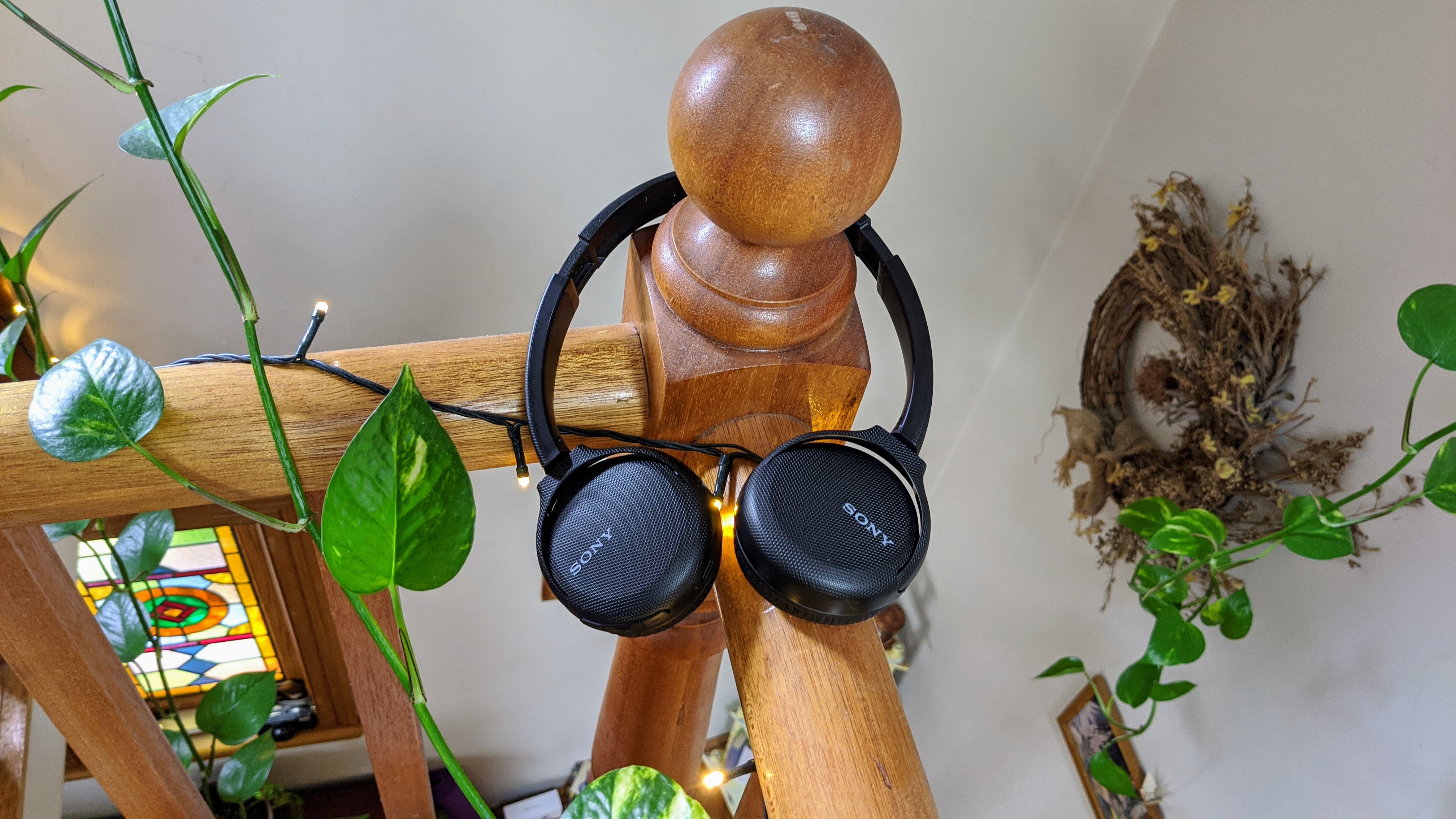 A pair of the Sony WH-CH510 on-ear headphones hanging on a wooden bannister