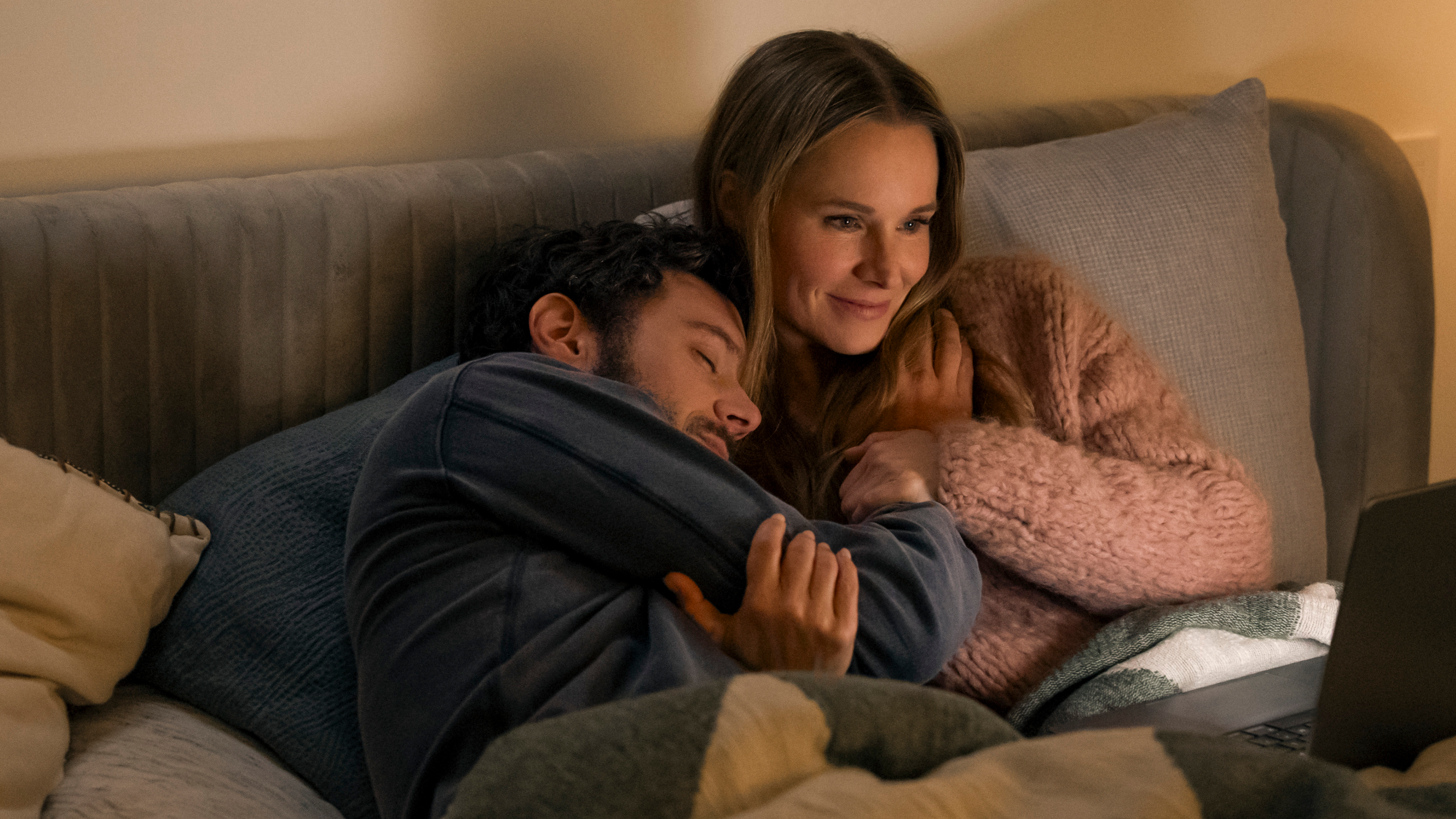 adam brody and kristen bell cuddle while watching a show on a laptop in nobody wants this season 2