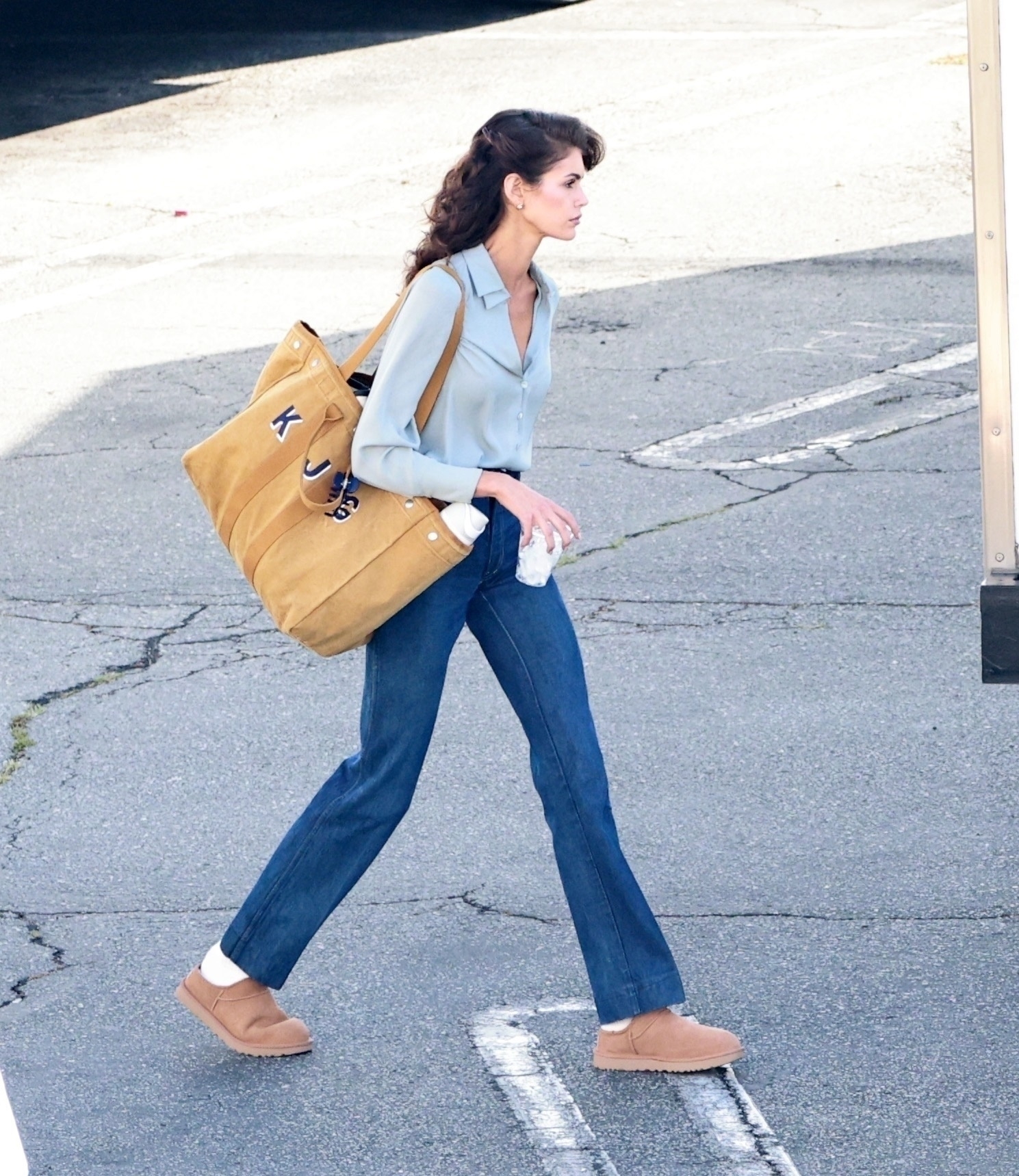 Kaia Gerber styled Uggs classic micro slippers with flared, dark-denim jeans and an Alex Mill tote bag