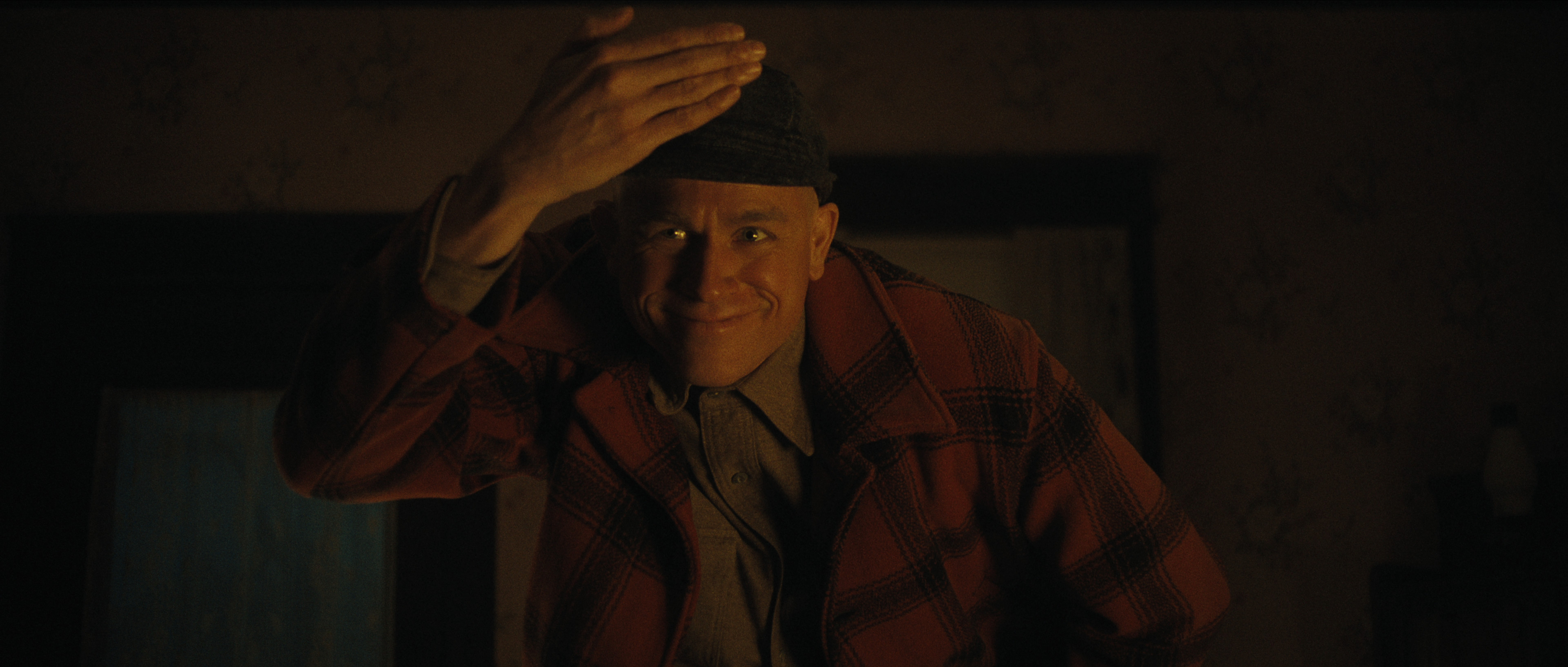 charlie hunnam as ed gein tapping his hat and wearing a plaid jacket in monster