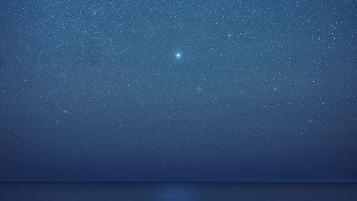 Sirius shining amongst a background of stars above a body of water.