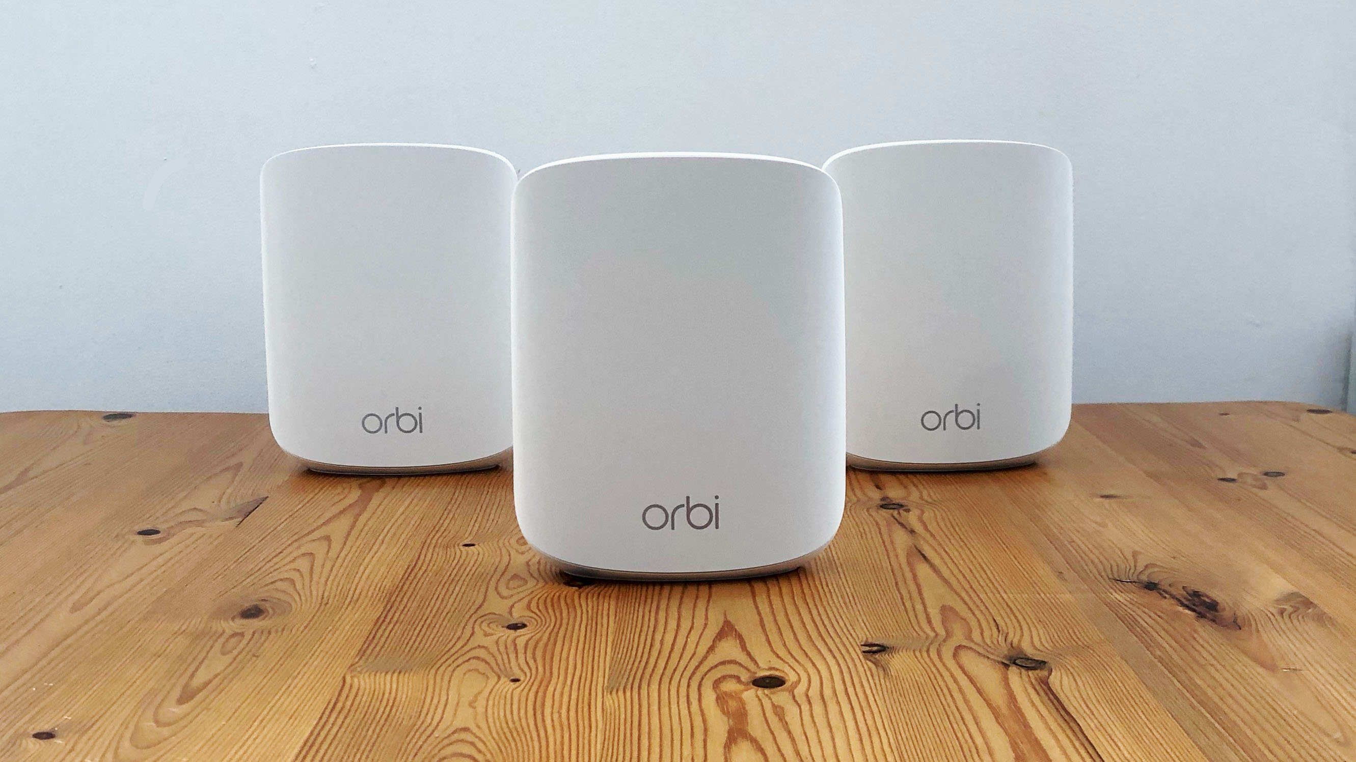 Netgear Orbi RBK353 on a wooden table in front of a white background
