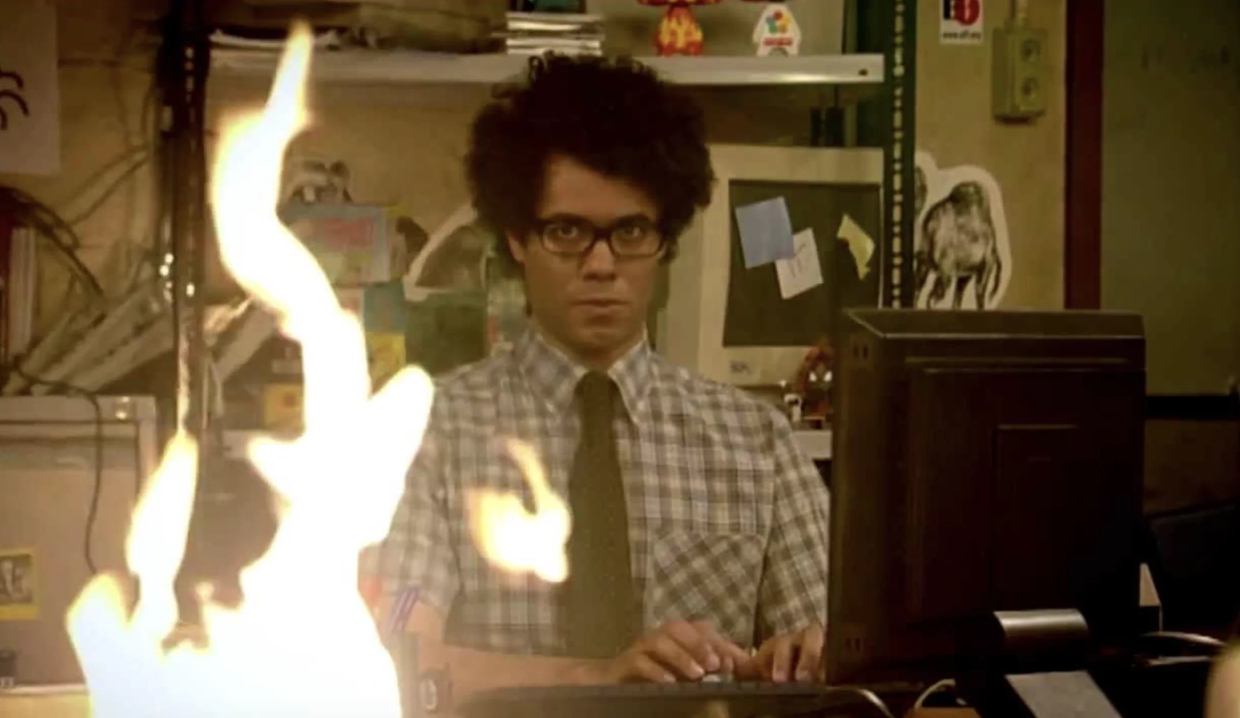 richard ayoade sits in front of a flame in the it crowd