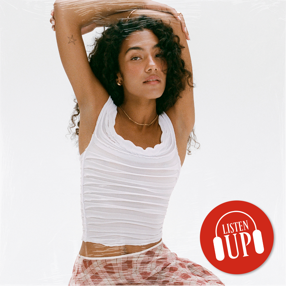 an image of singer olivia dean in a white shirt and red check skirt lifting her hands over her heads the logo for marie claire's listen up franchise on top