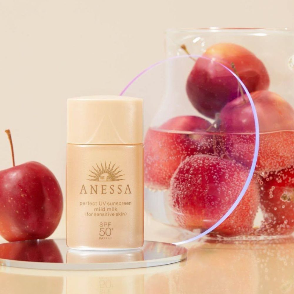 Anessa Perfect sunscreen mild milk next to a bowl of red apples