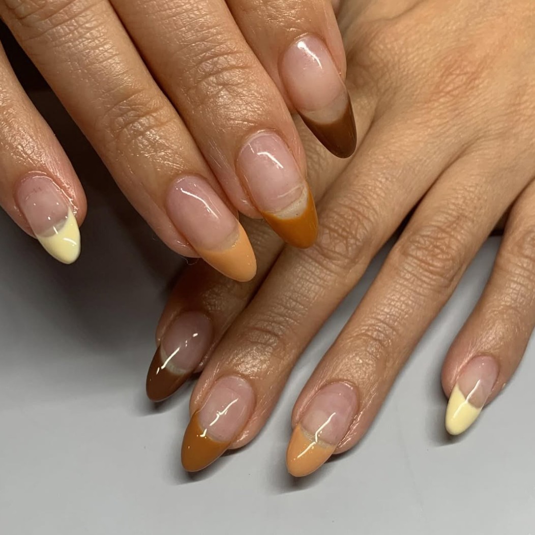 A pair of hands with different nude-colored French tips.