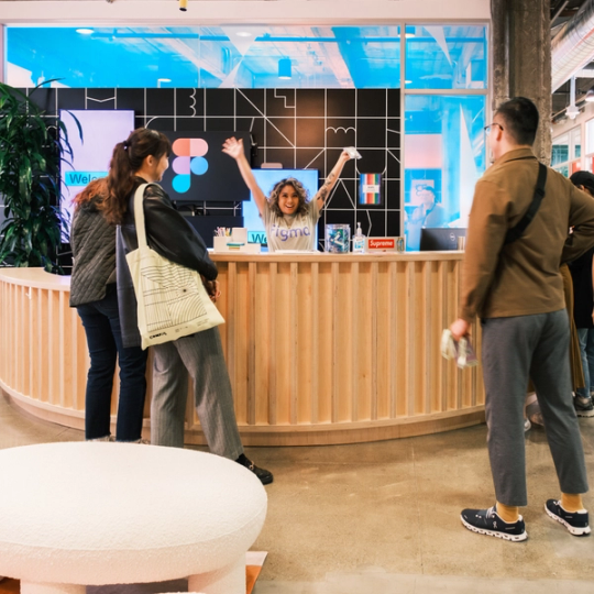 A group of Figma workers at the front desk of one of the offices