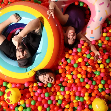 Three Figma employees in a ball pit with floaties smiling up at the camera