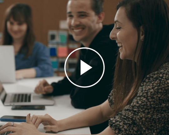 Video frame still of two people laughing while working, that links to a video on Decathlon and Linear