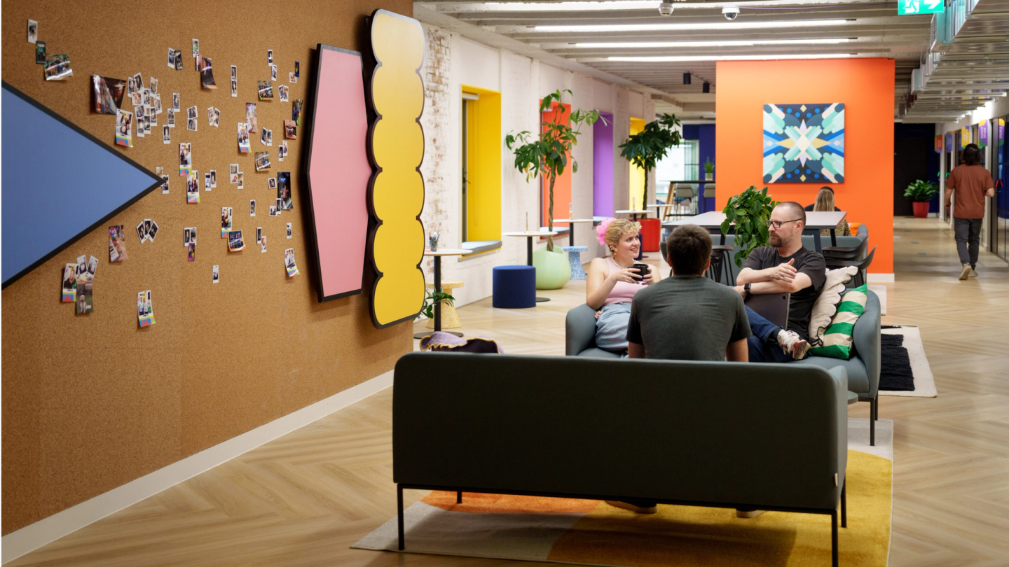 Three Figma employees on a couple of couches talking to each other in an office